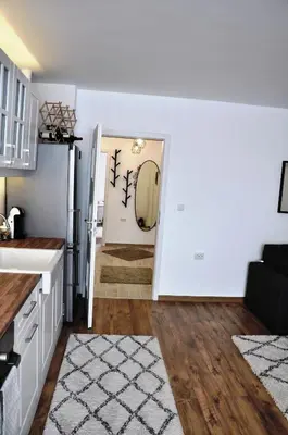 a kitchen and living room with white walls and wood floors at Lux Apartment in Pazardzhik