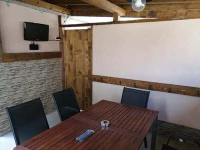 a room with a wooden table and chairs and a tv at Къща за гости Мира in Strelcha