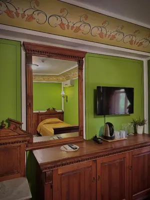 a bedroom with green walls and a mirror and a bed at Family Hotel at Renaissance Square in Plovdiv