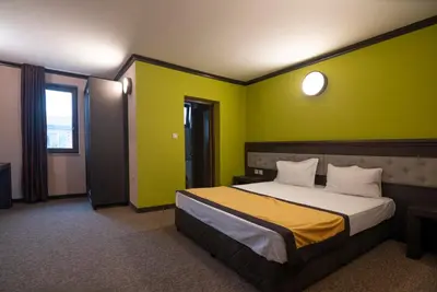 a bedroom with a large bed with green walls at Family Hotel Bunara in Brestnik
