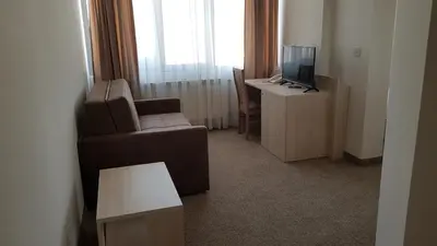 a living room with a chair and a desk with a television at SPS Hotel in Plovdiv