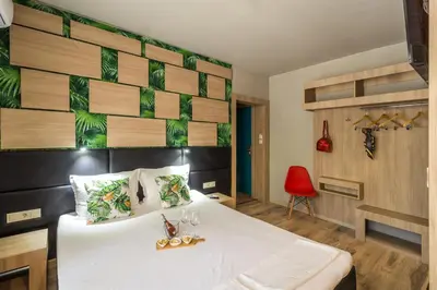 a bedroom with a white bed and a red chair at Hotel Allur in Plovdiv