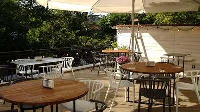 a patio with tables and chairs and an umbrella at Family Hotel Ramira in Kyustendil
