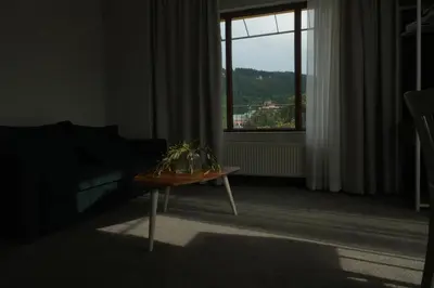 a living room with a couch and a table and a window at Family Hotel Ramira in Kyustendil