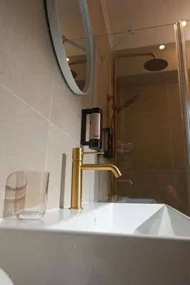 a bathroom sink with a gold faucet and a mirror at Family Hotel Ramira in Kyustendil
