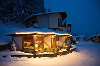 a building with lights in the snow at night at Amampuri Village in Pamporovo