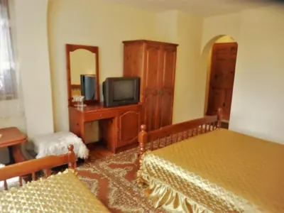 a bedroom with two beds and a tv and a dresser at Boyadjiyski Guest House in Bansko
