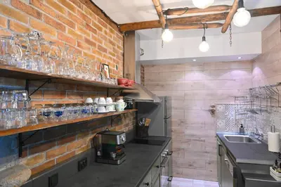 a kitchen with a brick wall with glasses on the shelves at Klecherova House in Bansko
