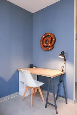 a desk with a white chair next to a blue wall at Artemis Apartments in Sandanski