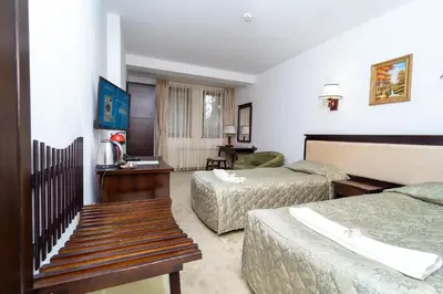 a hotel room with two beds and a bench at MPM Family Hotel Merryan in Pamporovo