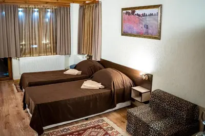 a hotel room with two beds and a chair at Matsurev Han in Bansko