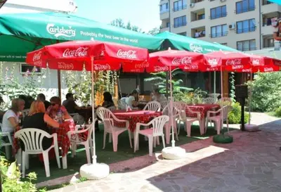 a group of people sitting at tables under cocacola umbrellas at Sky Rooms in Sofia