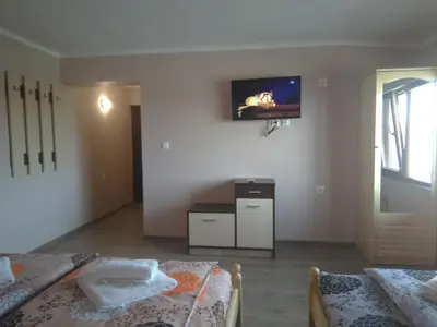 a room with two beds and a tv on the wall at ИВАНЕЛИ in Sapareva Banya