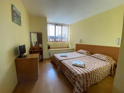a hotel room with two beds and a television at Family House Oreha in Bansko