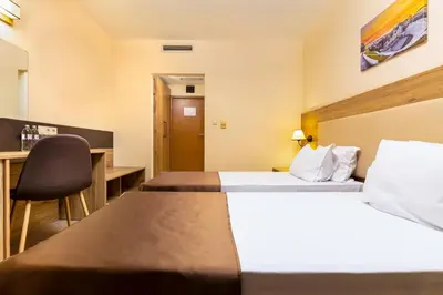 a hotel room with two beds and a desk at Hotel Intelcoop in Plovdiv