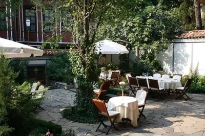 a patio with tables and chairs and an umbrella at Old Legends Hotel in Plovdiv