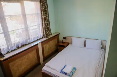 a small bedroom with a bed with a window at Къща за гости Типик in Bansko