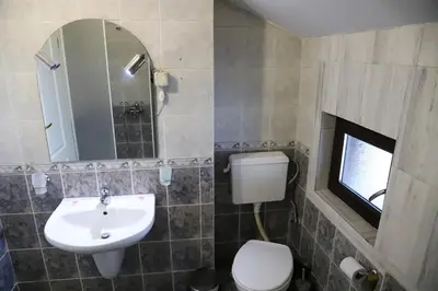 a bathroom with a sink and a toilet and a mirror at Къща за гости Типик in Bansko