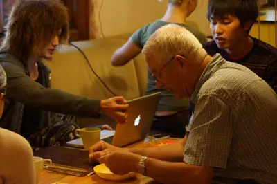 a group of people sitting around a table with a laptop at Hostel Mostel Hub Rooms and Apartments in Sofia