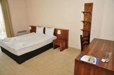 a bedroom with a bed and a wooden table at 3 Mountains Hotel in Bansko