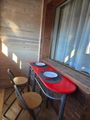 a red table and chairs in a room with a window at Pirina Club Hotel in Bansko