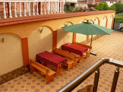 a balcony with two benches and an umbrella at Kashta Peychevi in Govedartsi