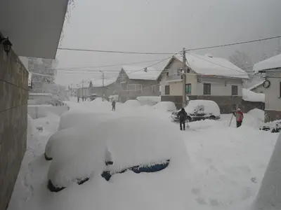 a car covered in snow in a yard at Family hotel Iskar in Govedartsi