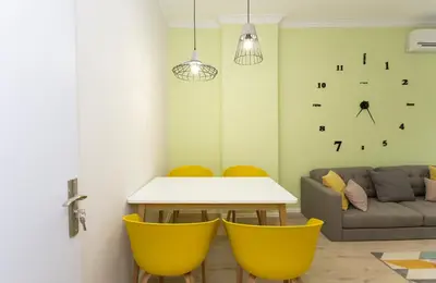 a living room with a table and yellow chairs at The Cozy Apartment, Sofia in Sofia