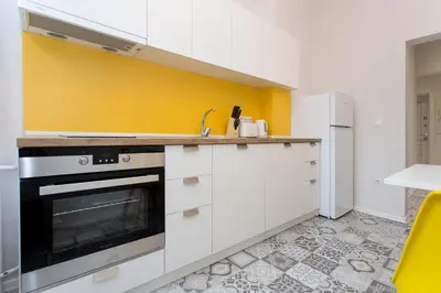a kitchen with white cabinets and a yellow wall at The Cozy Apartment, Sofia in Sofia