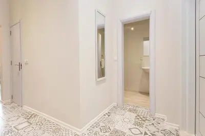 a bathroom with white walls and a door with a mirror at The Cozy Apartment, Sofia in Sofia
