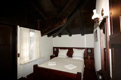 a bedroom with a bed with white sheets and a window at Family hotel Makedonska Kruchma in Dobrinishte