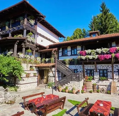 a large building with two benches in front of it at Family hotel Makedonska Kruchma in Dobrinishte