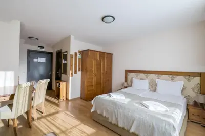 a bedroom with a bed and a table and chairs at Cornelia Deluxe Residence in Bansko