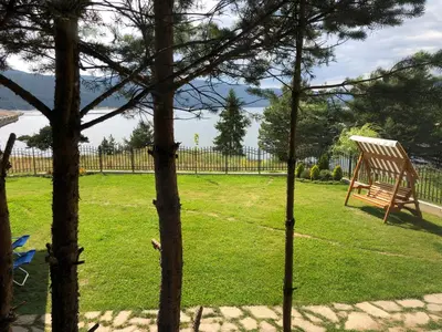a wooden chair sitting in the grass in a yard at Villa SUNRISE in Dospat