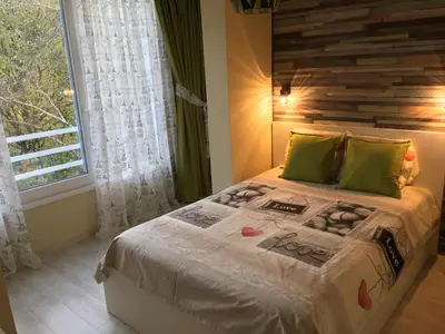 a bedroom with a bed with a wooden headboard and a window at Evergreen Sofia Apartment in Sofia