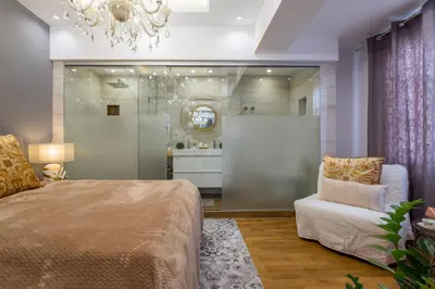 a bedroom with a bed and a chair and a chandelier at Parliament Sofia - Top Center Luxury Apartment in Sofia