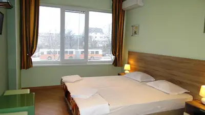 a bedroom with two beds and two windows at Guest Rooms Kom in Sofia