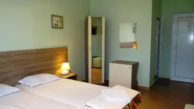 a bedroom with a large white bed and a mirror at Guest Rooms Kom in Sofia