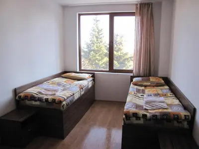two beds in a room with a window at Aparthotel Pine Hills Pamporovo in Pamporovo