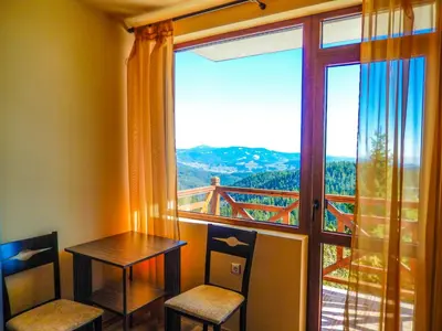 a room with a table and chairs and a large window at Aparthotel Pine Hills Pamporovo in Pamporovo