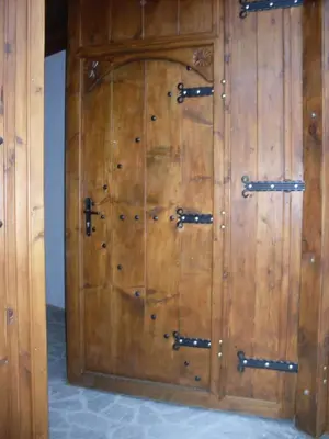 a wooden door with metal hinges on a wall at Tsutsovi House in Kalofer