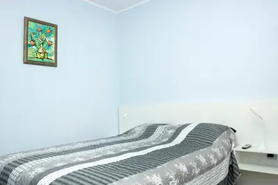 a bed in a white room with a picture on the wall at Cozy Apartment in the very centre of Sofia in Sofia