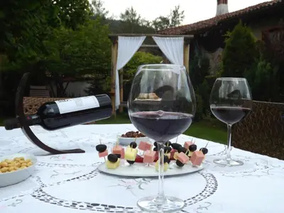 two glasses of wine sitting on a table with food at The Gates Apartments in Koprivshtitsa