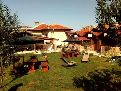 a yard with chairs and umbrellas in front of a house at Къща Момина сълза in Sapareva Banya