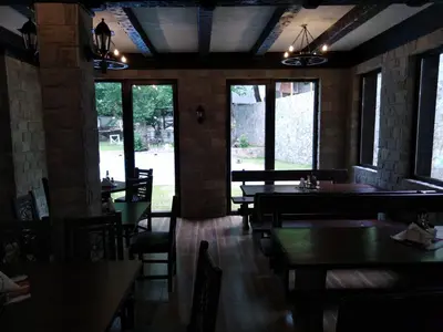 a dining room with tables and chairs and windows at Complex Magic of the Rhodopes in Bachkovo