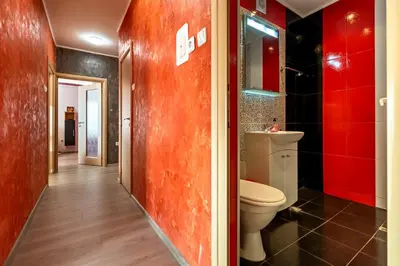 a bathroom with a toilet and a red wall at Apartments Rosina in Plovdiv