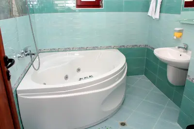 a bathroom with a white tub and a sink at Къщи за гости Илиеви , Цигов Чарк in Batak