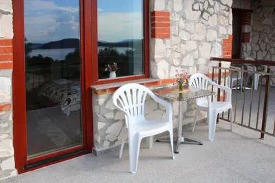 two white chairs and a table on a porch at Къщи за гости Илиеви , Цигов Чарк in Batak