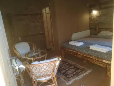a bedroom with a bed and a table and chairs at Скендерова Къща Къщичка Алиса in Leshten