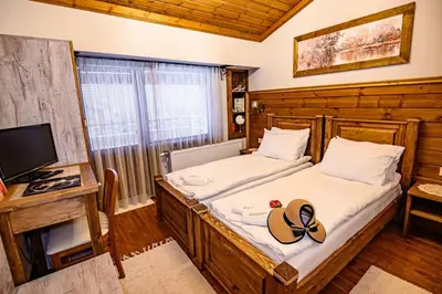 a bedroom with two beds and a tv in a room at Къща за гости Плевнята in Bansko